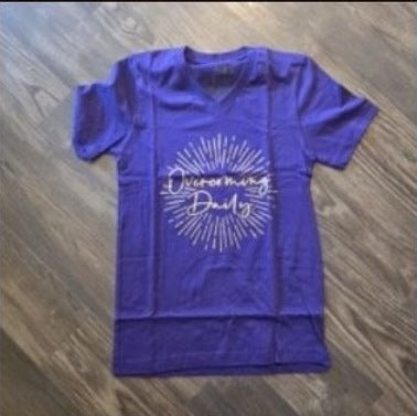 Overcoming Daily Tee | Purple photographed on wood floor